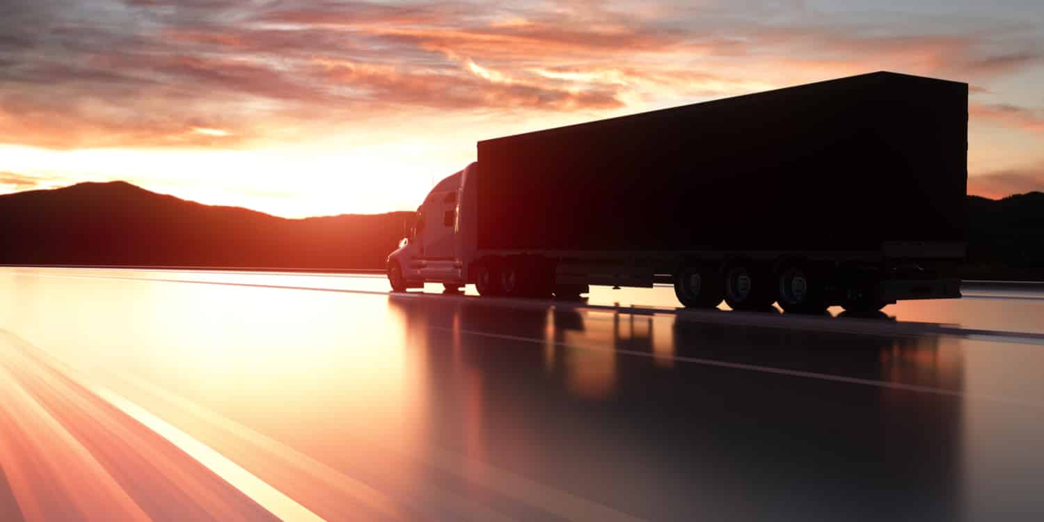 A semi-truck on the highway at sunset, representing trucking statistics