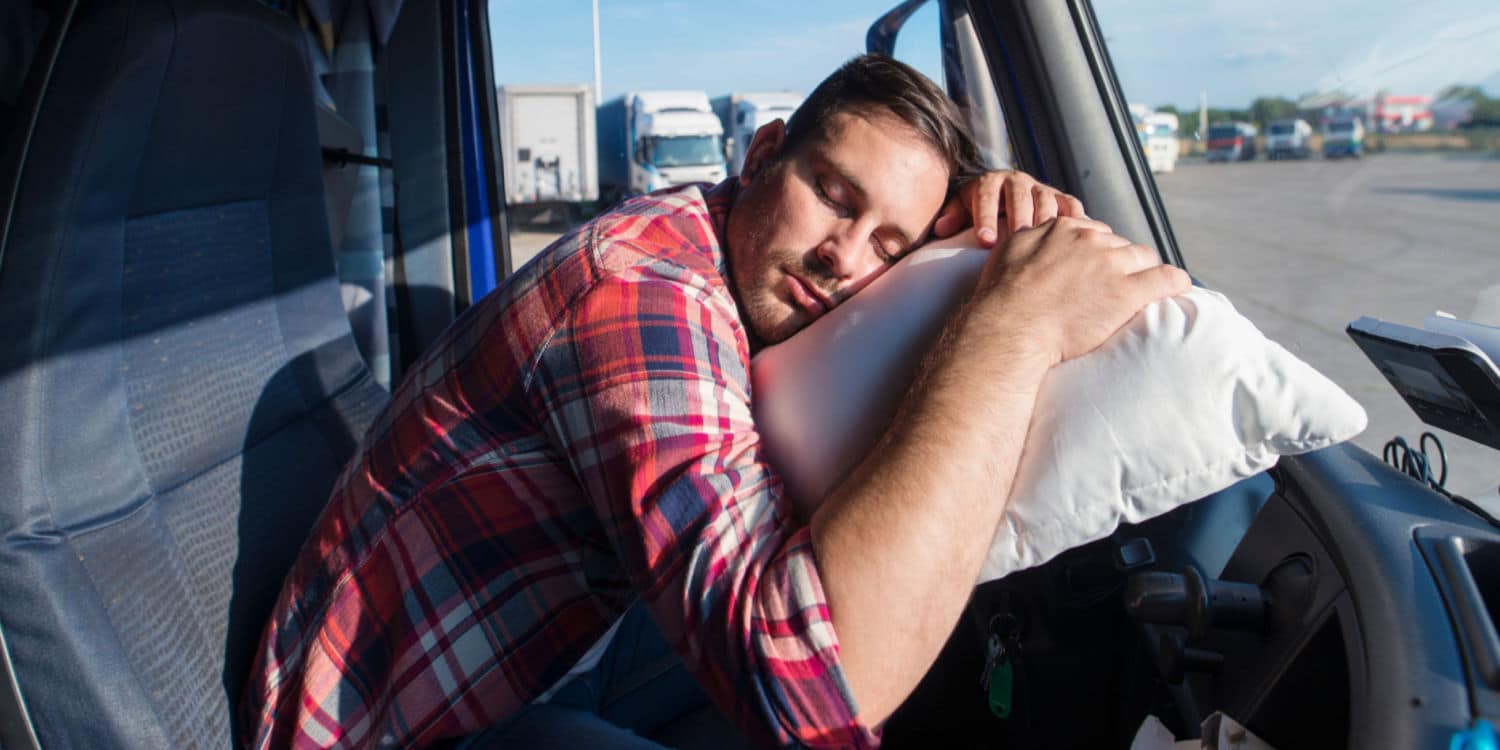 An OTR trucker sleeping on a pillow on his steering wheel