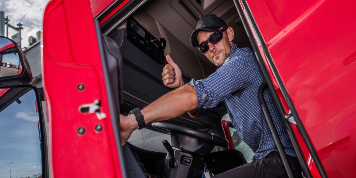 A man sitting in a semi-truck giving a thumbs up to show that trucking is a great career for veterans