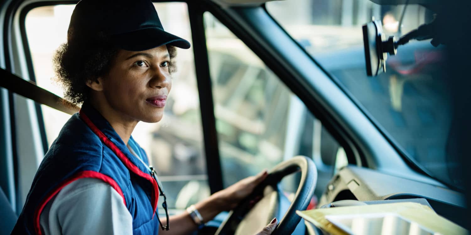 A woman behind the wheel of a semi-truck benefitting from great truck driving pay
