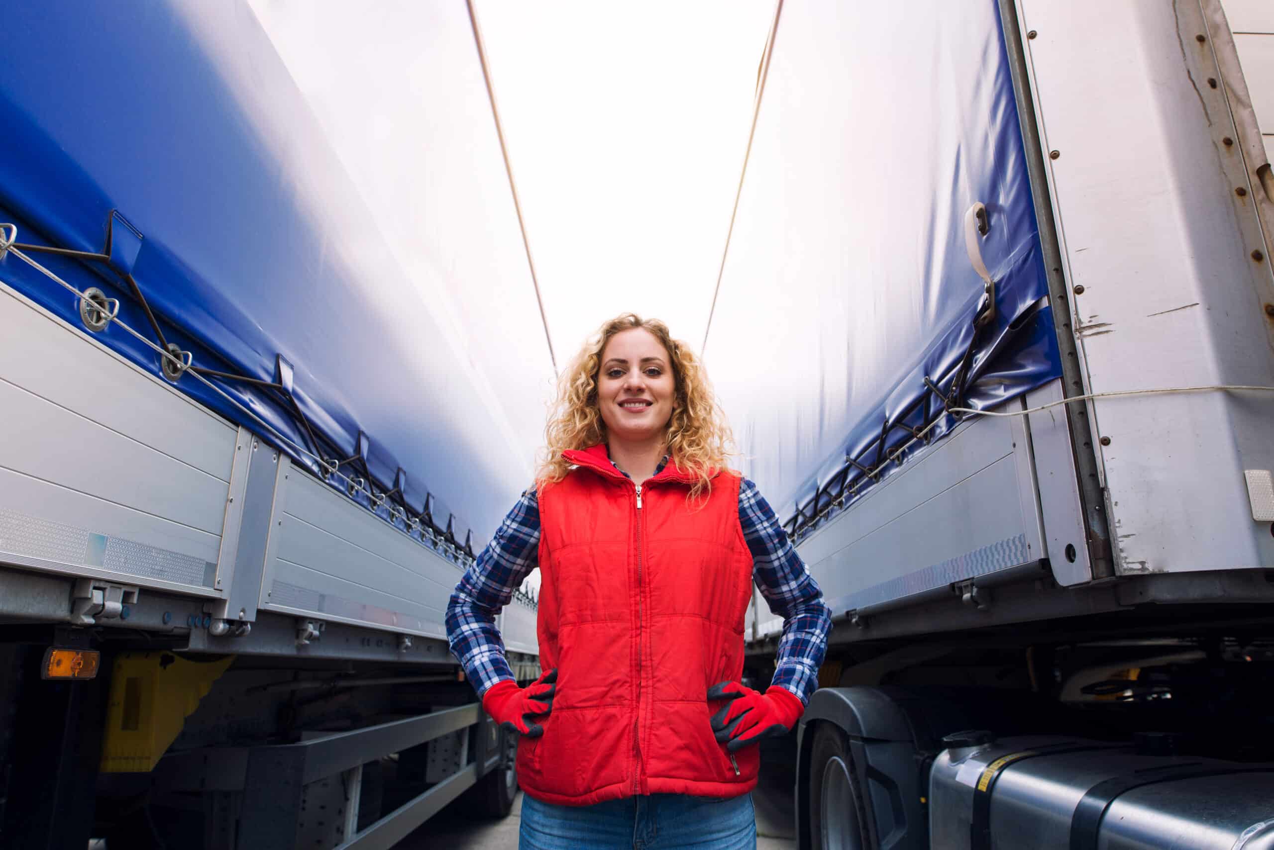 a woman trucker in a red vest standing in a trailer