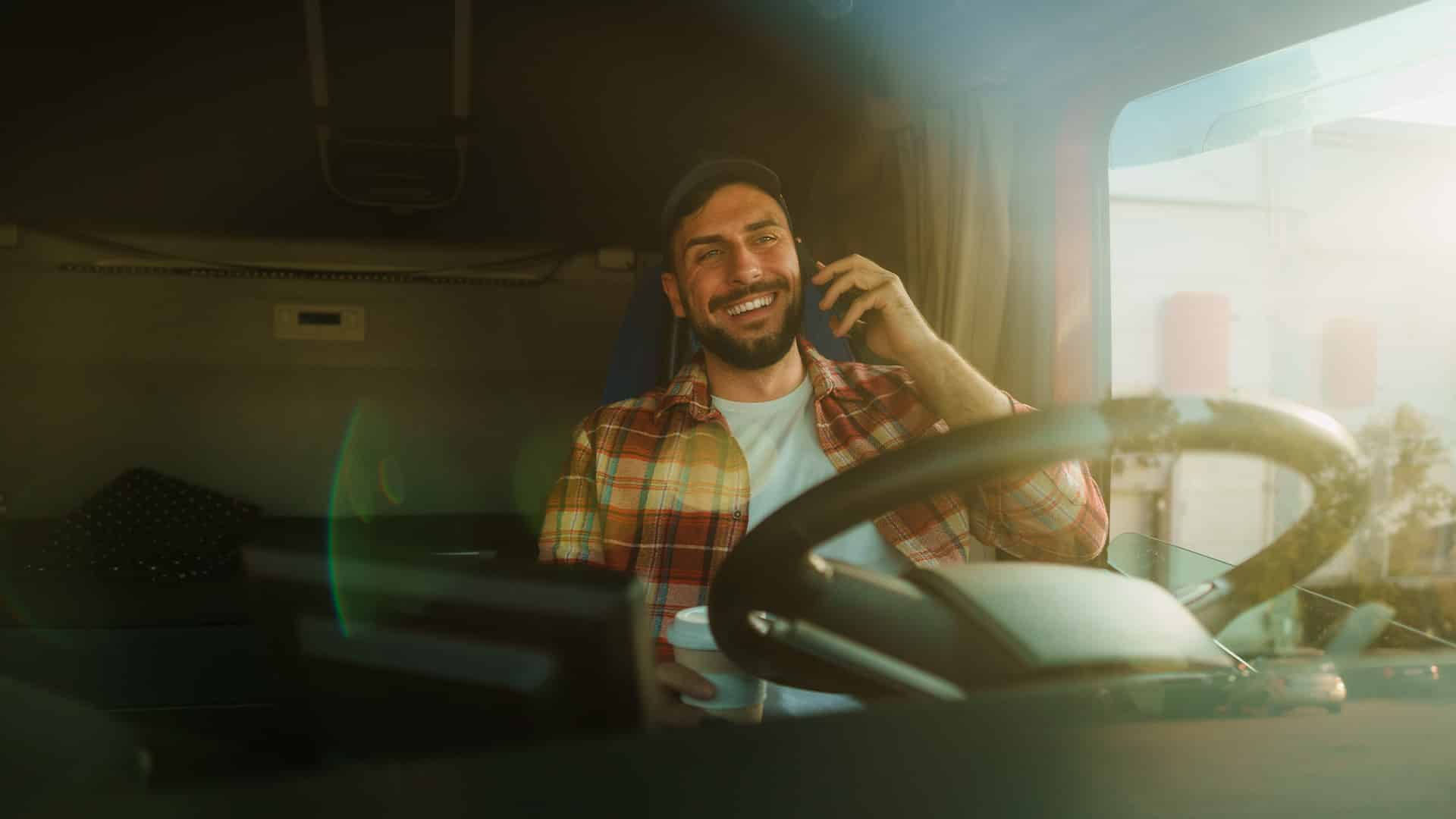 truck driver chatting on the phone in a big rig