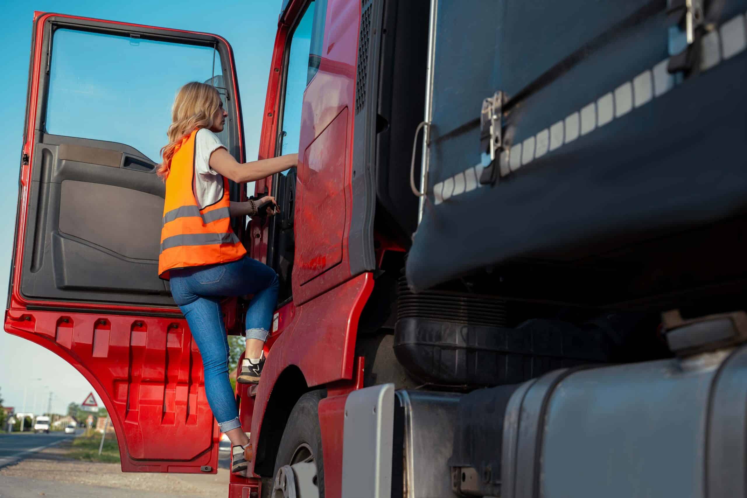 Person in a safety vest climbing into a red truck on a sunny day